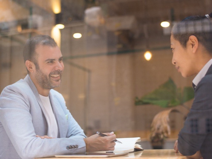 Dos personas conversando frente a frente en una cafetería con luz cálida